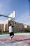 On an urban court, strong athlete plays basketball alone with an orange ball