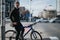 Urban cyclist waiting at a crosswalk with a blue bicycle in a city setting