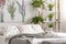 Urban jungle bedroom interior with plants in pots beside a bed dressed in organic cotton linen of white color with green print. Re