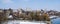 Urban landscape in early spring. Bare trees affected by mistletoe, buildings, river and blue sky