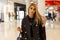 Urban pretty fashionable young woman blonde in an elegant coat in a black blouse in plaid pants with a fashionable leather bag