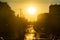 Urban scene. Cars stand at the traffic light. Silhouettes riding bike and walking on pedestrian street in golden sunset