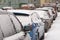 Urban scene of street with parked snow-covered cars