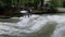 Urban surfers ride the standing wave on the Eisbach River, Munich, Germany