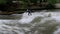 Urban surfers ride the standing wave on the Eisbach River, Munich, Germany