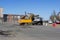 Urban sweeper with yellow trailer cleans road from dirt with a round brush in the spring at the crossroads of five roads. Gatchina