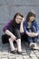 Urban teen girls sitting at stone wall