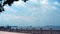 Urban walkway and a fence with water and cloudscape in the background