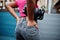 Urban young african american woman in pink top and grey jeans with handbag. Afro fashion chic women back buttocks