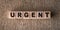 URGENT - word written on wooden blocks on a brown background