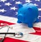 US of America health budget. Medical stethoscope, protective mask and piggy bank on a USA flag, closeup view