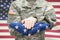 US Army young soldier holding carefully folded USA flag before his chest