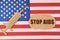 On the US flag there is a cardboard figure of a syringe and a torn cardboard with the inscription - STOP AIDS