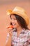 USA cowgirl eating peach nectarine fruit smiling wearing cowboy hat at outdoor country farm . Healthy food farmers