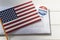 USA flag and Envelope with voting ballot papers sent by mail for absentee vote in presidential election. Top view with copy space