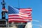 USA flag on pole on ferry`s stern. Ongoing cruise to islands. Blue sky background