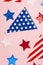 USA Independence Day concept. Top view vertical photo of national flag garland and stars on isolated pastel pink background