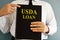 USDA Loan concept. Man holding book.