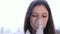 Use nebulizer and inhaler for the treatment. Young woman inhaling through inhaler mask. Close-up face, front view.