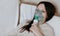 Use nebulizer and inhaler for the treatment. Young woman inhaling through inhaler mask lying on the couch. Closeup front