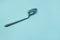 A used and bent spoon, isolated on a blue background.