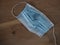 Used and broken 3-ply blue surgical mask to cover the mouth and nose with rubber ear straps. Protection mask from bacteria and