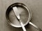 Used clean empty stainless steel frying pan and spatula overhead view on the gray background