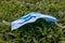 Used face surgical mask dumped on the grass during the Covid-19 pandemic.