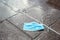 Used surgical face mask against infection with coronavirus and covid-19 carelessly thrown away into a puddle on the street, the