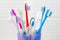 Used toothbrushes in various sizes in a plastic container in white bathroom
