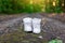 Used white high sneakers stand on a rural road that runs in the forest