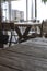 A used wooden table in the foreground, sharply focused. In the background there are more tables and chairs from the beach bar in