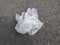 Used, wrinkled, white nitrile gloves thrown on dirt ground. Disposable security measure, ideal for protection against viruses and