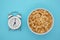 useful breakfast of cereal and alarm clock on blue table close-up