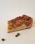 Useful pastries.  Appetizing piece of apple pie with pecans, caramel and coffee beans on a plain light background