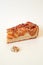 Useful pastries.  Appetizing piece of apple pie with pecans, caramel and half a walnut on a plain light background