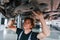 Uses wrench to fix car. Adult man in grey colored uniform works in the automobile salon