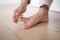 Using a brush, the person gently brushes their foot on the hardwood flooring