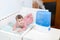 Using humidifier for prevent pulmonary disease, infant child lying in cot next to ultrasonic device