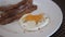 using knife and fork cutting egg yolk to eat fried egg in white plate. Cutting sunny side up egg with runny egg yolk