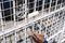 Using a small paint roller to repaint white colored epoxy paint on a steel grille fence of a carport