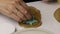 Using a stamp, a woman applies a pattern to gingerbread cookie blanks