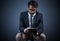 Using technology to get ahead. Studio shot of a handsome young businessman using a tablet while sitting on a chair