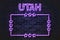 Utah US State glowing violet neon letters and starred frame on a black brick wall
