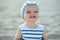 Ð¡ute baby girl in nice striped dress and blue headband smiling and showing her first teeth