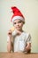 Ð¡ute girl in Santa Claus hat eat cookies.