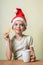 Ð¡ute girl in Santa Claus hat eat cookies.