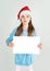 Ð¡ute girl in Santa Claus hat with a white blank paper sheet wit