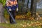 A utility worker in a special uniform uses a blower to remove fallen leaves from a park lawn. Yellow leaves are flying