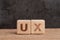 UX User Experience design in product and service concept, cube wooden block building acronym UX on table with blackboard with copy